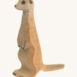 Light brown standing meerkat on a cream background
