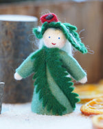 Close up of an Ambrosius yew Christmas fairy figure on a white floor next to some small logs and dried oranges