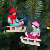 Close up of the Ambrosius handmade sledging boy and girl Christmas decorations hanging from a Christmas tree