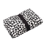 A baby lying down and looking at the colourful Leopard print on the Etta Loves Reversible Organic Cotton Baby Play Mat - Animal Print