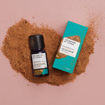 Atlas Cedar pure essential oil in a blue glass bottle next to a decorative blue cardboard box on a background of brown wood dust.. 
