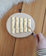 Adult hand holding a wooden mallet over the Auris junior glockspiel on a wooden floor