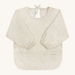 A light Avery row long sleeve bib with a daisy design on the front on a cream background.