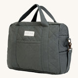 A dark charcoal colour Avery Row changing bag on a cream background.
