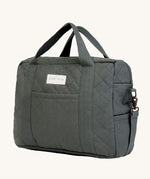 A dark charcoal colour Avery Row changing bag on a cream background.