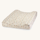 A soft light coloured Avery Row changing cushion mat with a grasslands design on a cream background.