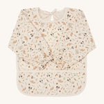 A light cream Avery Row long sleeve  baby bib with a grassland design on a cream background.