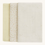 A soft light coloured Avery Row set of three muslin squares including a light with a wild chamomile design muslin, a daisy design and a light green muslin on a cream background.