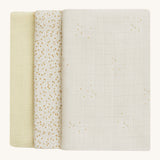 A soft light coloured Avery Row set of three muslin squares including a light with a wild chamomile design muslin, a daisy design and a light green muslin on a cream background.