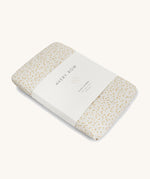 A Avery row muslin swaddle with a daisy flower design on a cream background.
