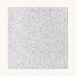 A soft light blue Avery row muslin swaddle with a nature trails design on a cream background