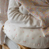 A close up of the Avery Row Nursing Pillow with an Anemone design in use. The The top of the pillow features a white background with a delicate pink anemone flower print. Avery Row have a range of baby and nursery products with stylish designs available at Babipur. 