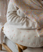 A close up of the Avery Row Nursing Pillow with an Anemone design in use. The The top of the pillow features a white background with a delicate pink anemone flower print. Avery Row have a range of baby and nursery products with stylish designs available at Babipur. 