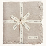 A soft beige Avery row knitted blanket on a cream background.