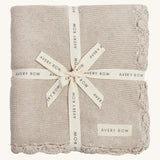 A soft beige Avery row knitted blanket on a cream background.
