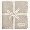 A soft beige Avery row knitted blanket on a cream background.