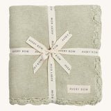 A soft willow colour Avery Row knitted blanket on a cream background.