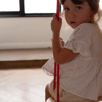 Close up of child sat on a Babai eco-friendly wooden rope swing in a bright living room