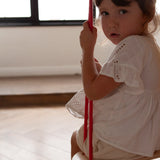 Close up of child sat on a Babai eco-friendly wooden rope swing in a bright living room