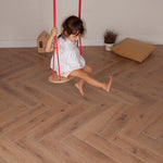Child swinging on the Babai eco-friendly rope swing set above a wooden living room floor