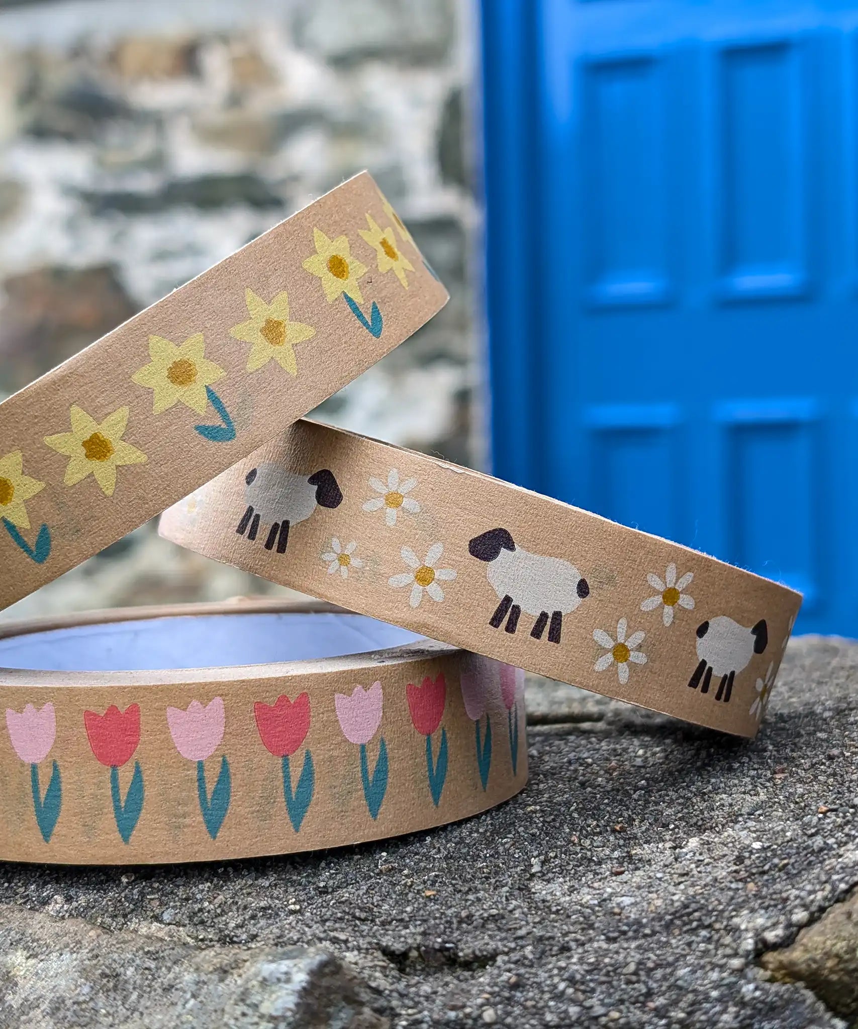 Babipur eco kraft paper tapes with three different Spring design on a wall outdoors. Daffodils, sheep and daisies and pink tulips.