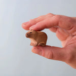 Bumbu Toys Wooden Baby Capybara, being held in an adult's hand.