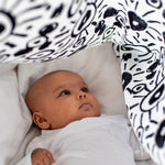 A child breastfeed with the parent using the muslin cloth on their arm/shoulder
