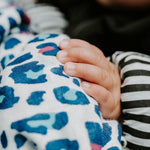 A baby looking up at the red and light blue Leopard print on the Etta Loves Organic Cotton Baby Muslin Squares 3 Pack - Leopard