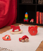 Red coloured wooden Bajo toys placed on a white rug. These heirloom quality toys by Bajo are part of a wide range of wooden toys available here at Babipur.