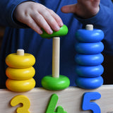 A close up of a child playing with a Bajo 1-5 pull along stacking toy