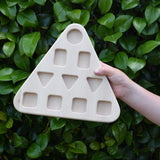 The base piece from the Bajo 10 piece sorting board held up in a child's hand.