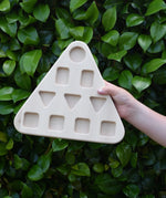 The base piece from the Bajo 10 piece sorting board held up in a child's hand.