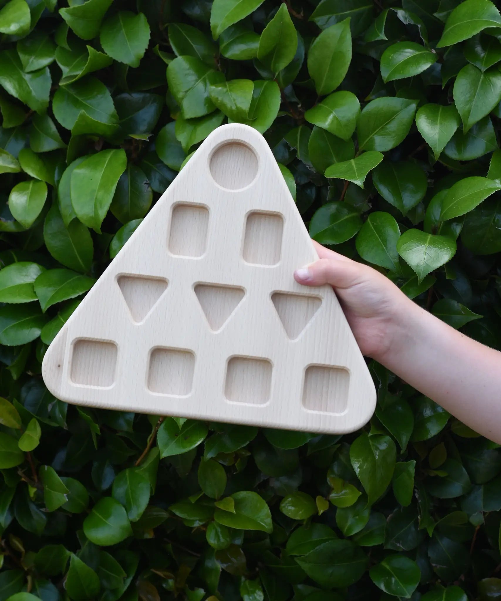 The base piece from the Bajo 10 piece sorting board held up in a child's hand.