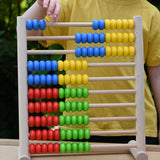 Child playing with the Bajo 100 Bead Abacus counting toy, moving blue coloured counter along the top bar. 