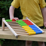 Bajo 100 Bead Abacus counting toy placed on a Miri slide set up as a table outoors.