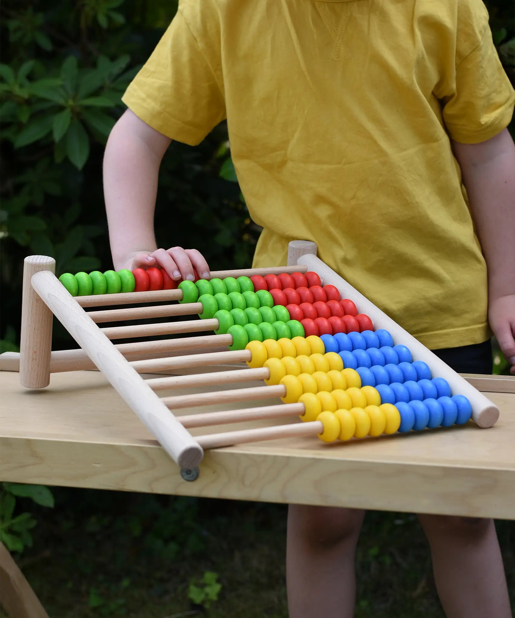 Bajo 100 Bead Abacus counting toy placed on a Miri slide set up as a table outoors.