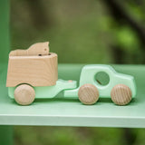 Bajo mint green 4x4 car and horse trailer wooden toy placed on a shelf.