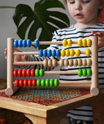 Child playing with the Bajo 50 bead wide abacus in the Babipur playroom.