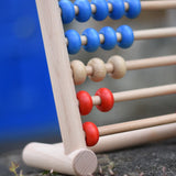 Close up of the Bajo 50 bead wide abacus placed on a stone wall.