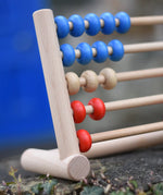 Close up of the Bajo 50 bead wide abacus placed on a stone wall.