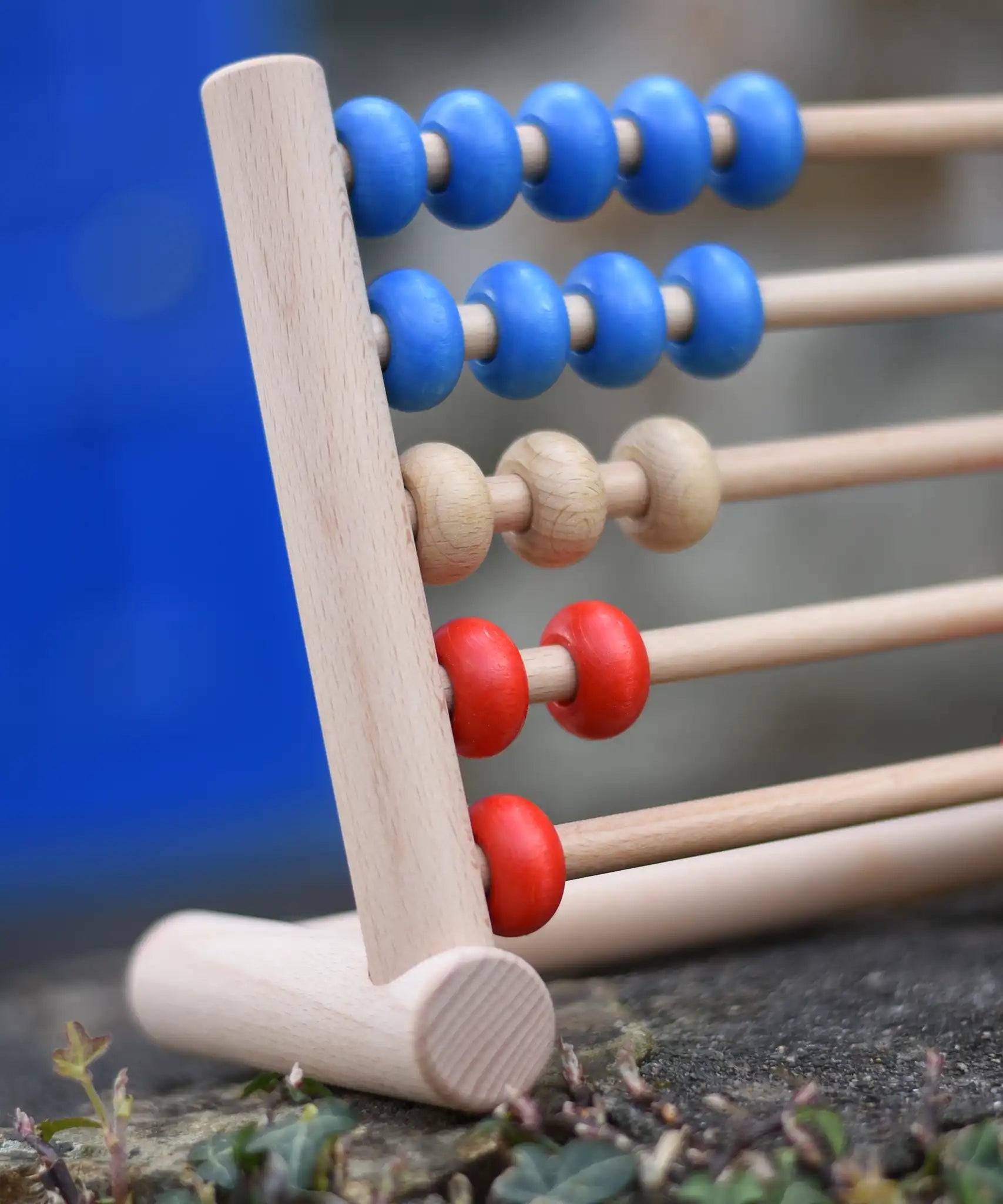 Close up of the Bajo 50 bead wide abacus placed on a stone wall.
