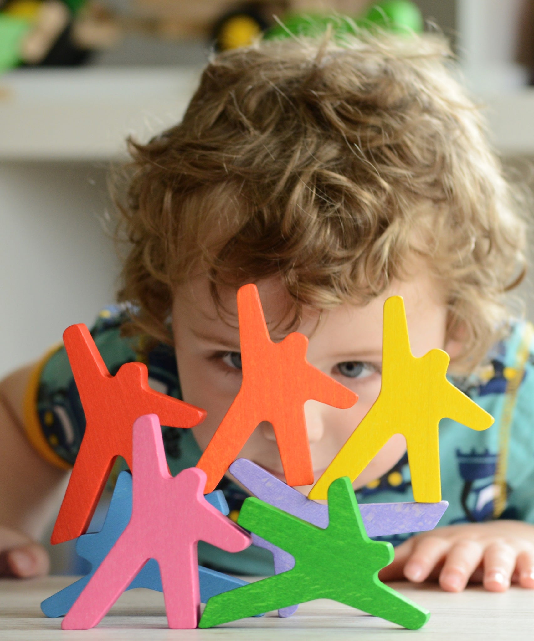A child peering through the stacked figures from the Bajo Acrobats balancing game. A set of 8 coloured wooden acrobat shaped figures. These heirloom quality toys by Bajo are part of a wide range of wooden toys available here at Babipur.