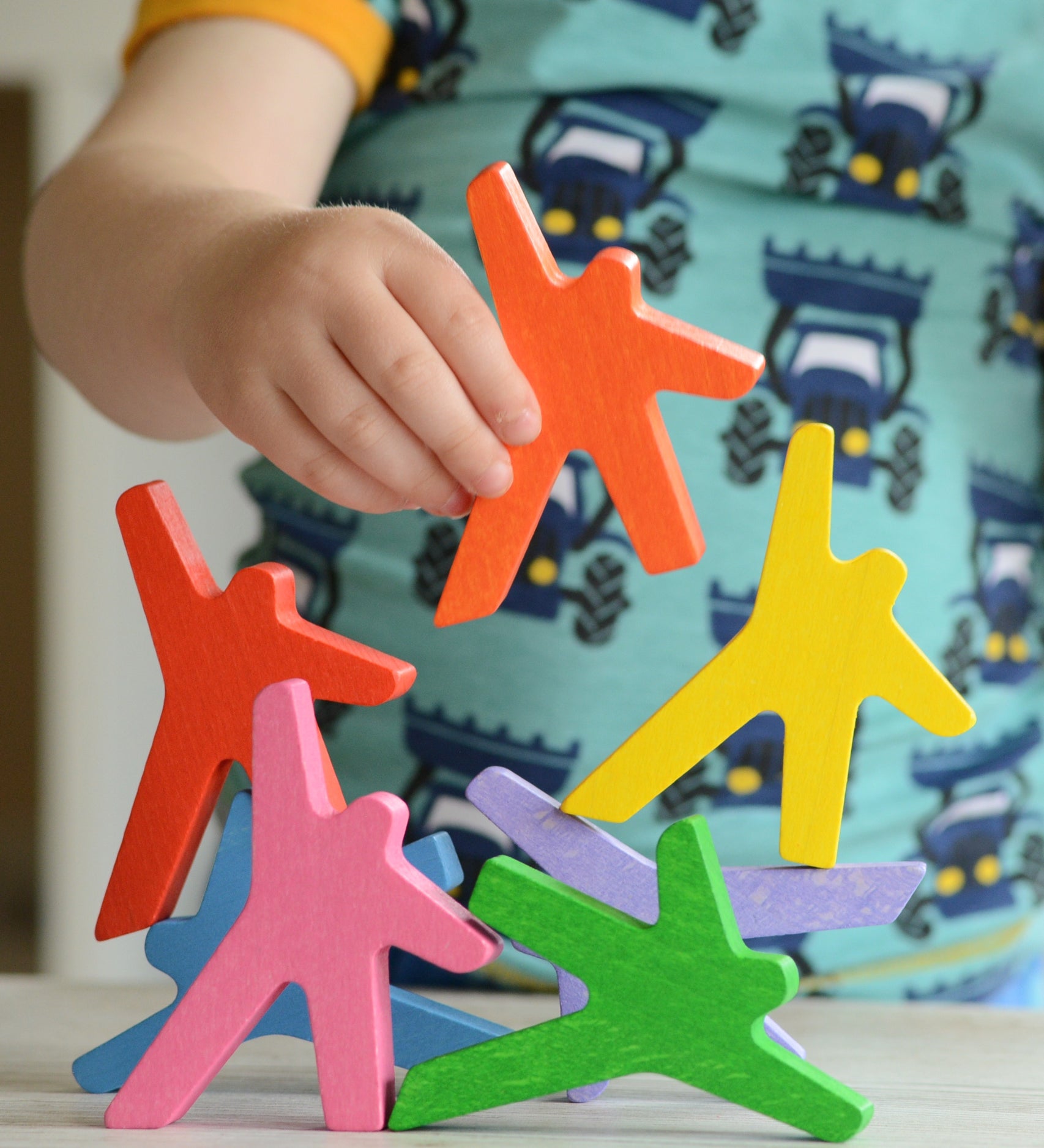 A close up of a child's hand playing with the Bajo Acrobats balancing game. A set of 8 coloured wooden acrobat shaped figures. These heirloom quality toys by Bajo are part of a wide range of wooden toys available here at Babipur.