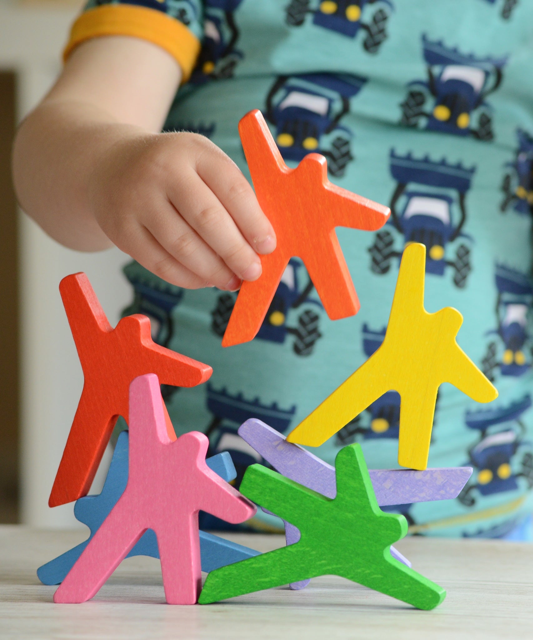 A close up of a child's hand playing with the Bajo Acrobats balancing game. A set of 8 coloured wooden acrobat shaped figures. These heirloom quality toys by Bajo are part of a wide range of wooden toys available here at Babipur.