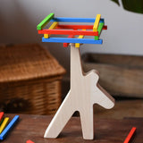 Bajo athlete wooden stacking balance game placed on a wooden surface with some of the wooden sticks balanced on the athlete shaped wooden figure base. 