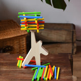 Bajo athlete wooden stacking balance game placed on a wooden surface with some of the wooden sticks balanced on the athlete shaped wooden figure base. 