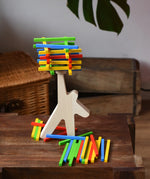 Bajo athlete wooden stacking balance game placed on a wooden surface with some of the wooden sticks balanced on the athlete shaped wooden figure base. 