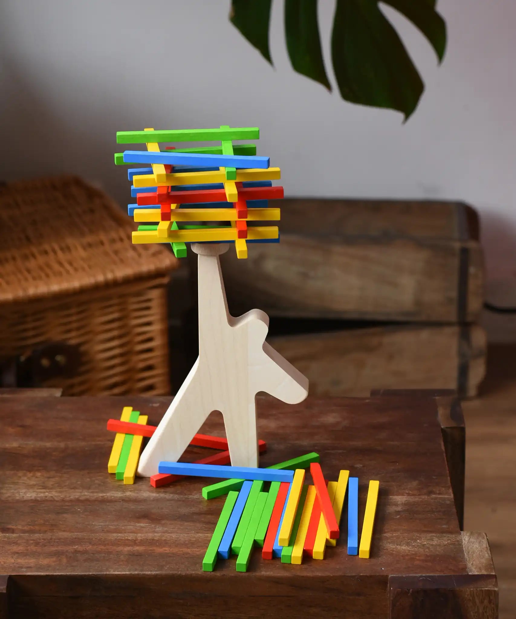 Bajo athlete wooden stacking balance game placed on a wooden surface with some of the wooden sticks balanced on the athlete shaped wooden figure base. 