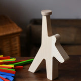Athlete shaped wooden figure base from the Bajo athlete wooden stacking balance game placed on a wooden surface with the wooden sticks placed besides it.