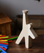 Athlete shaped wooden figure base from the Bajo athlete wooden stacking balance game placed on a wooden surface with the wooden sticks placed besides it.